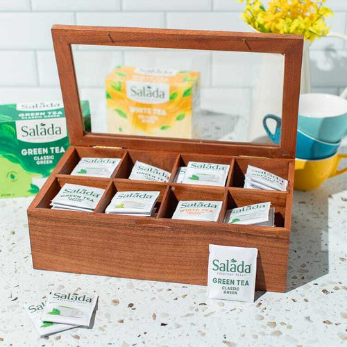 Salada tea chest, lid open and filled with tea on a counter